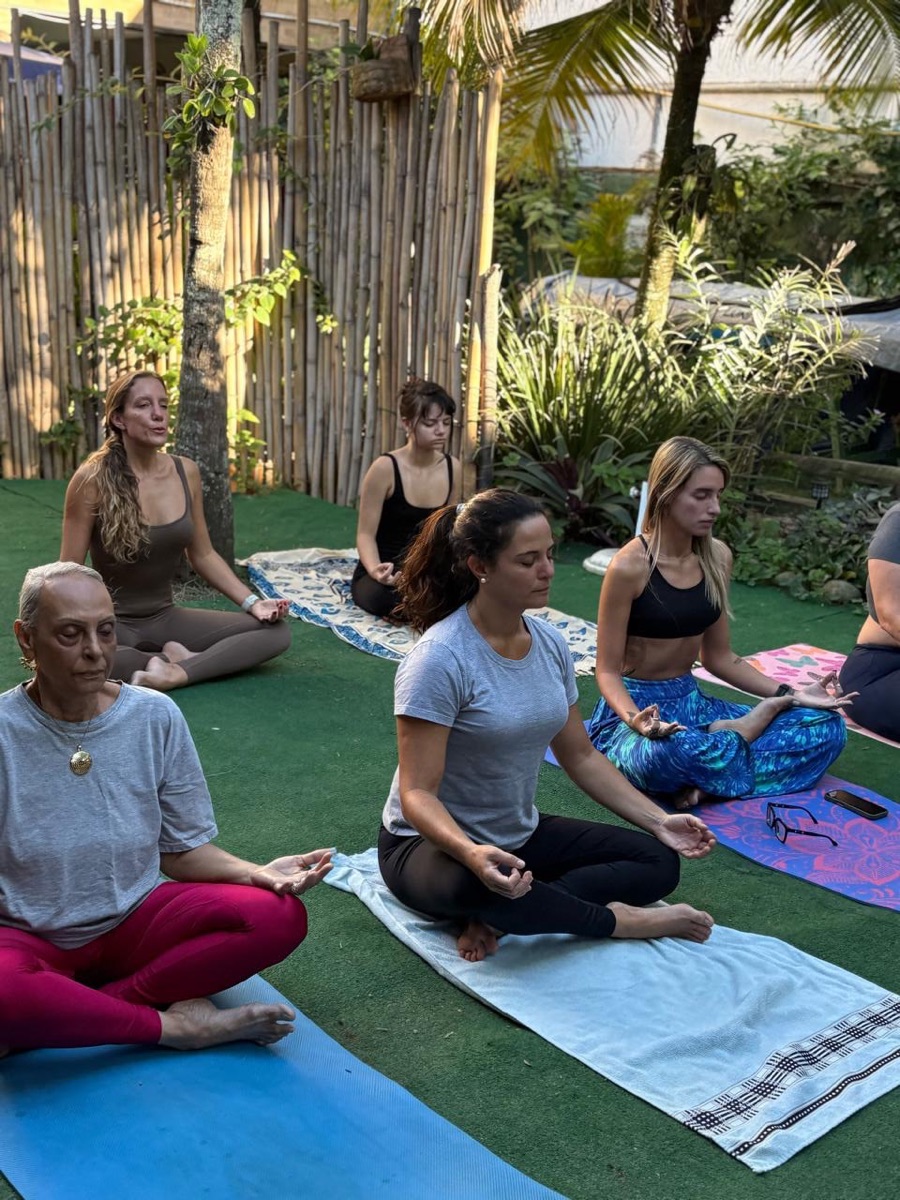 Aula de yoga no gramado do Vibes, com o jardim e a cerca de bambu ao fundo